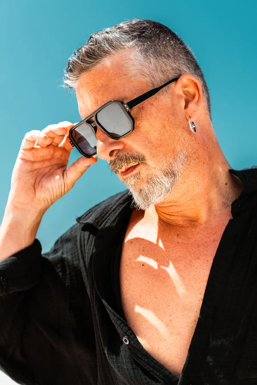 DJ INO wearing sunglasses against a turquoise sky